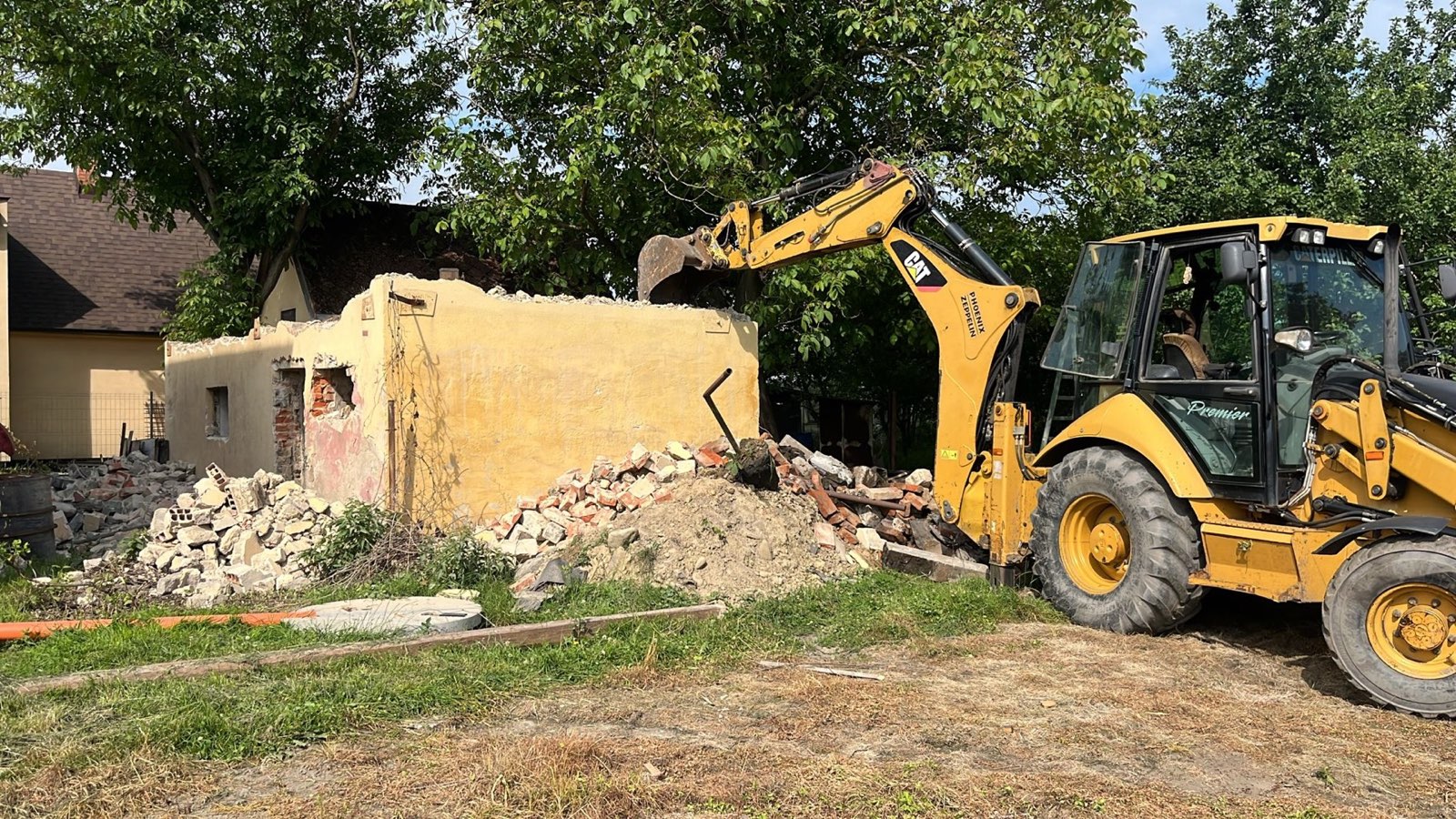 Rypadlo-nakladač CAT při demolici staré budovy