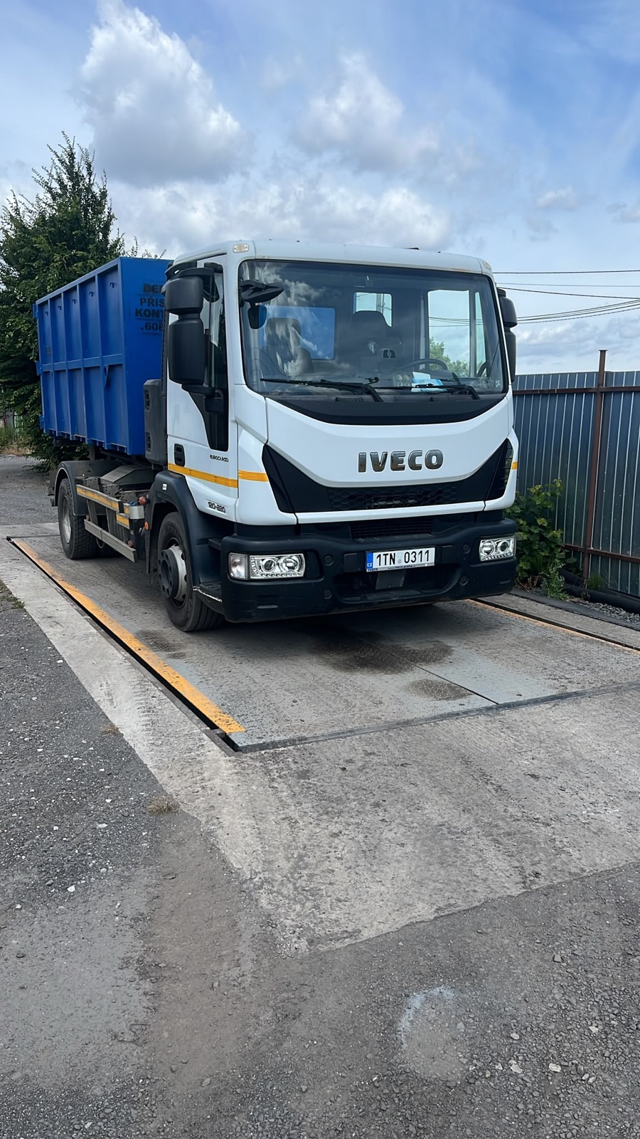 Nosič kontejnerů IVECO s modrým kontejnerem stojí na mostové váze v areálu ve Vratimově